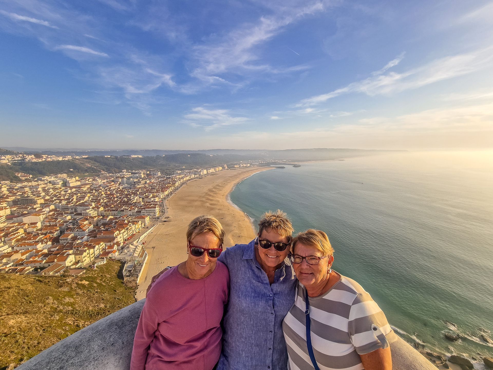 3 happy ladies in Stio in Nazare with the Ocean on their back during a transfer from Lisbon to Porto with Duca
