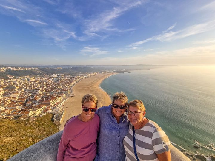 Three guests at a viewpoint in Nazaré with the ocean behind them during a transfer from Lisbon to Porto