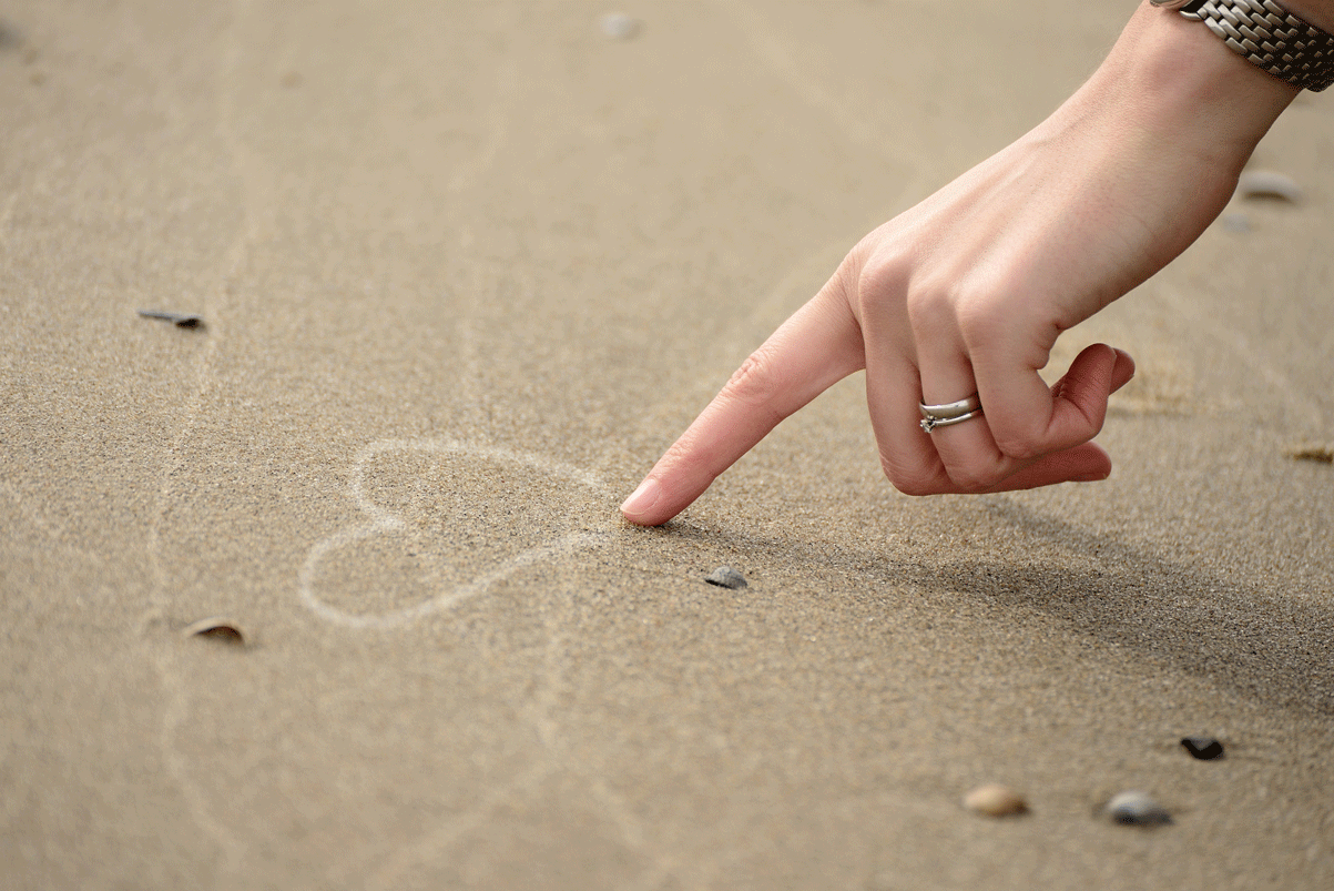 Eulogy Writing Services - person drawing a love heart in the sand by the beach