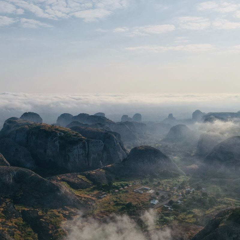 An aerial view of a valley surrounded by mountains and clouds.