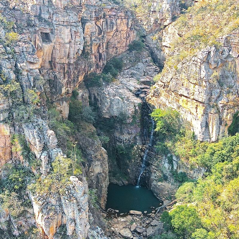 An aerial view of a waterfall in the middle of a canyon surrounded by trees.