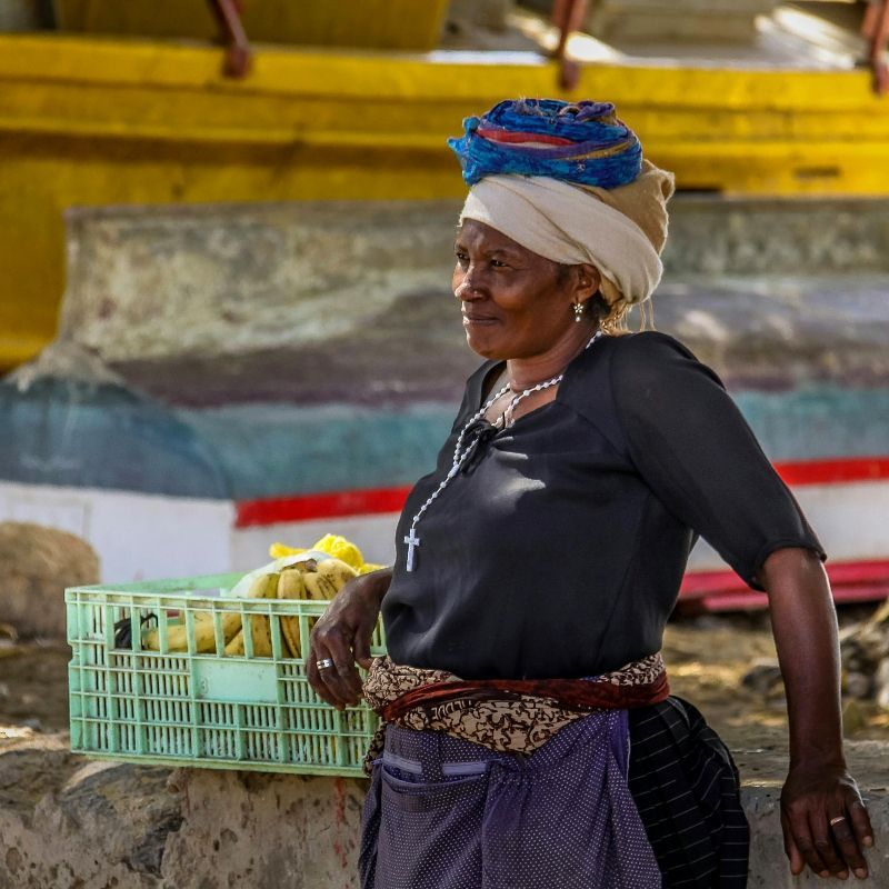 A vibrant image of a woman in traditional Cape Verdean clothing balancing a basket of tropical fruit on her head captures the rich culture and warm spirit of Cape Verde. This island nation offers diverse experiences—from the volcanic landscapes of Fogo and white-sand beaches of Sal to the lively music and colonial charm of São Vicente. Atlantur, a specialized DMC, expertly organizes tailor-made travel for FITs and groups across the islands. Discover Cape Verde’s unique blend of African and Portuguese heritage with local insight and seamless service. Experience the true soul of Cape Verde with Atlantur, your trusted travel partner.