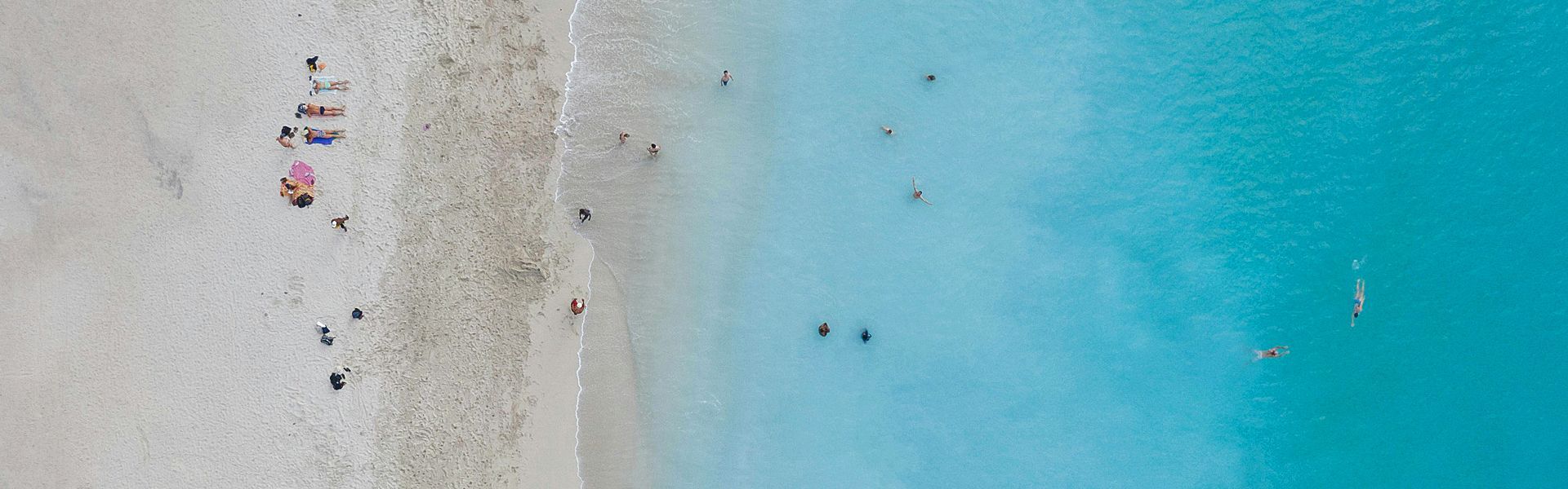 An aerial view of a beach with people swimming in the ocean.