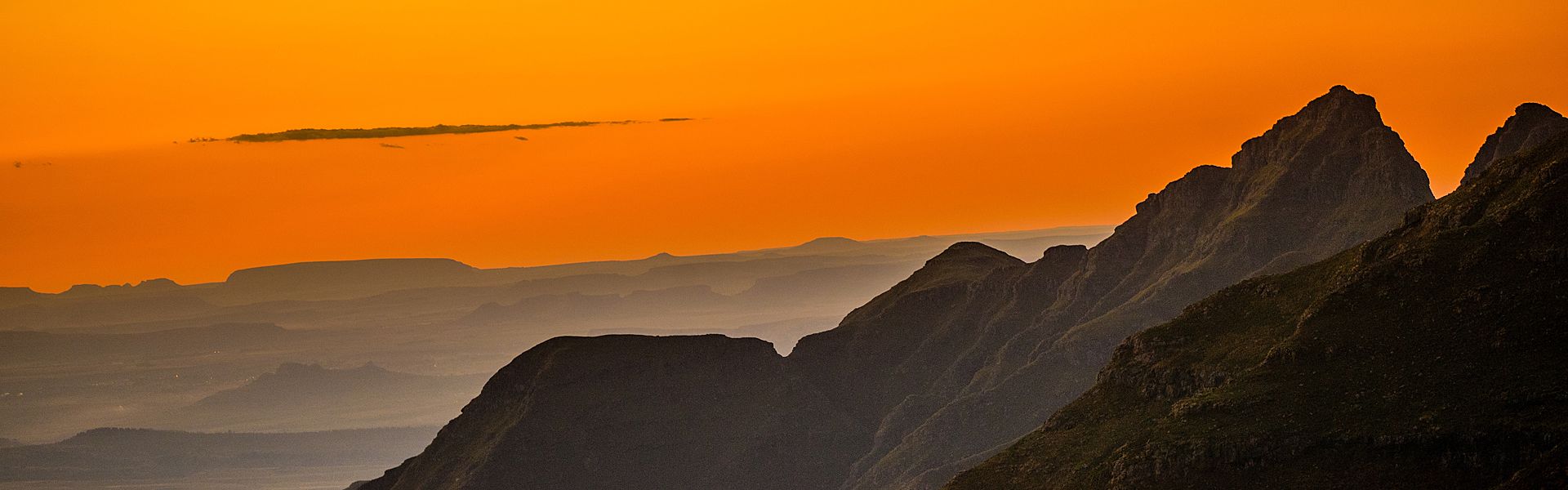 A helicopter is flying over a field at sunset.