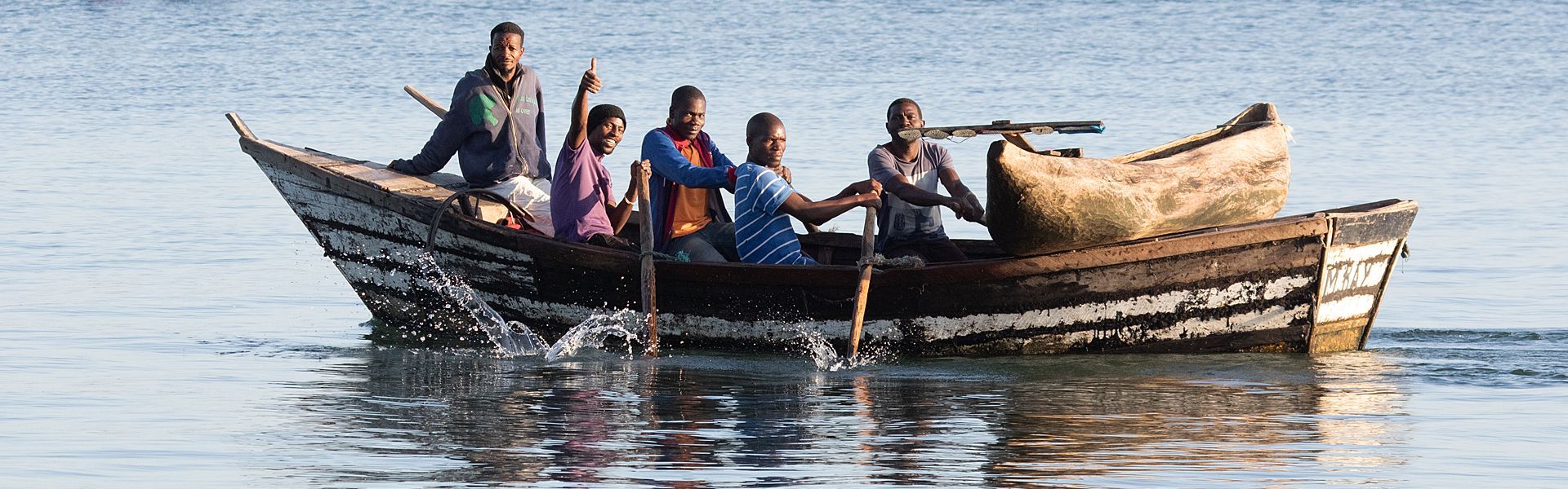 A group of people are rowing a boat in the water.