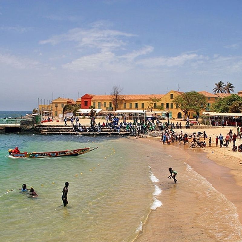 This evocative image captures a scene from Île de Gorée, where small boats float near the beach, people gather by the water, and historic buildings stand in the background—a powerful reminder of the island’s role in the transatlantic slave trade. Located just off the coast of Dakar, Gorée is both a place of remembrance and striking beauty, with colonial architecture, narrow streets, and a peaceful shoreline. Discover the cultural depth and emotional history of Senegal with CicoTours, your expert local partner. Africa DMC's, through its network of great locally based tour operators, organizes unforgettable journeys to this historic destination.