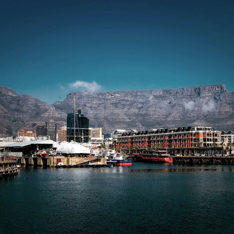 A city with a mountain in the background and a body of water in the foreground.