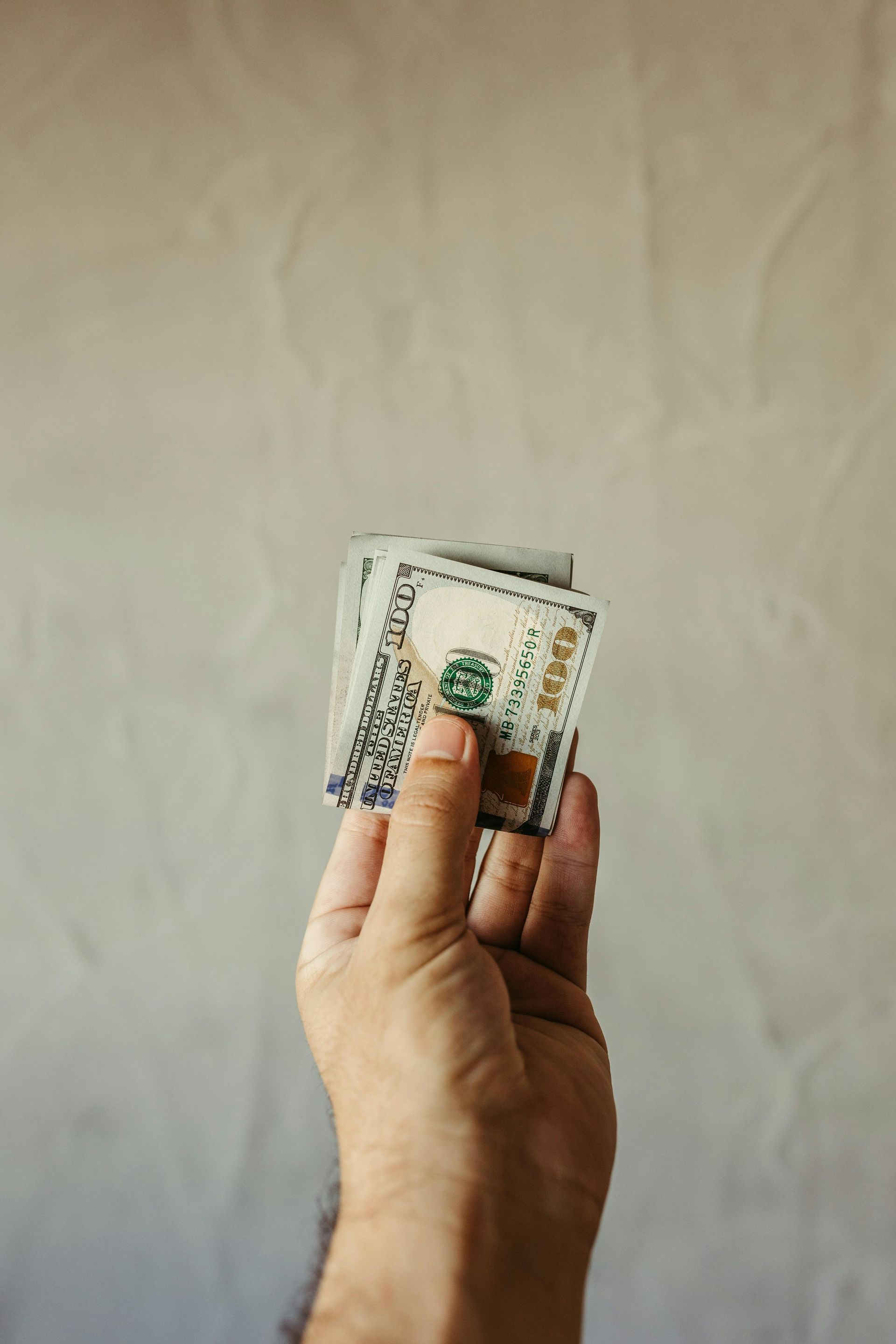 A person is holding a stack of money in their hand.