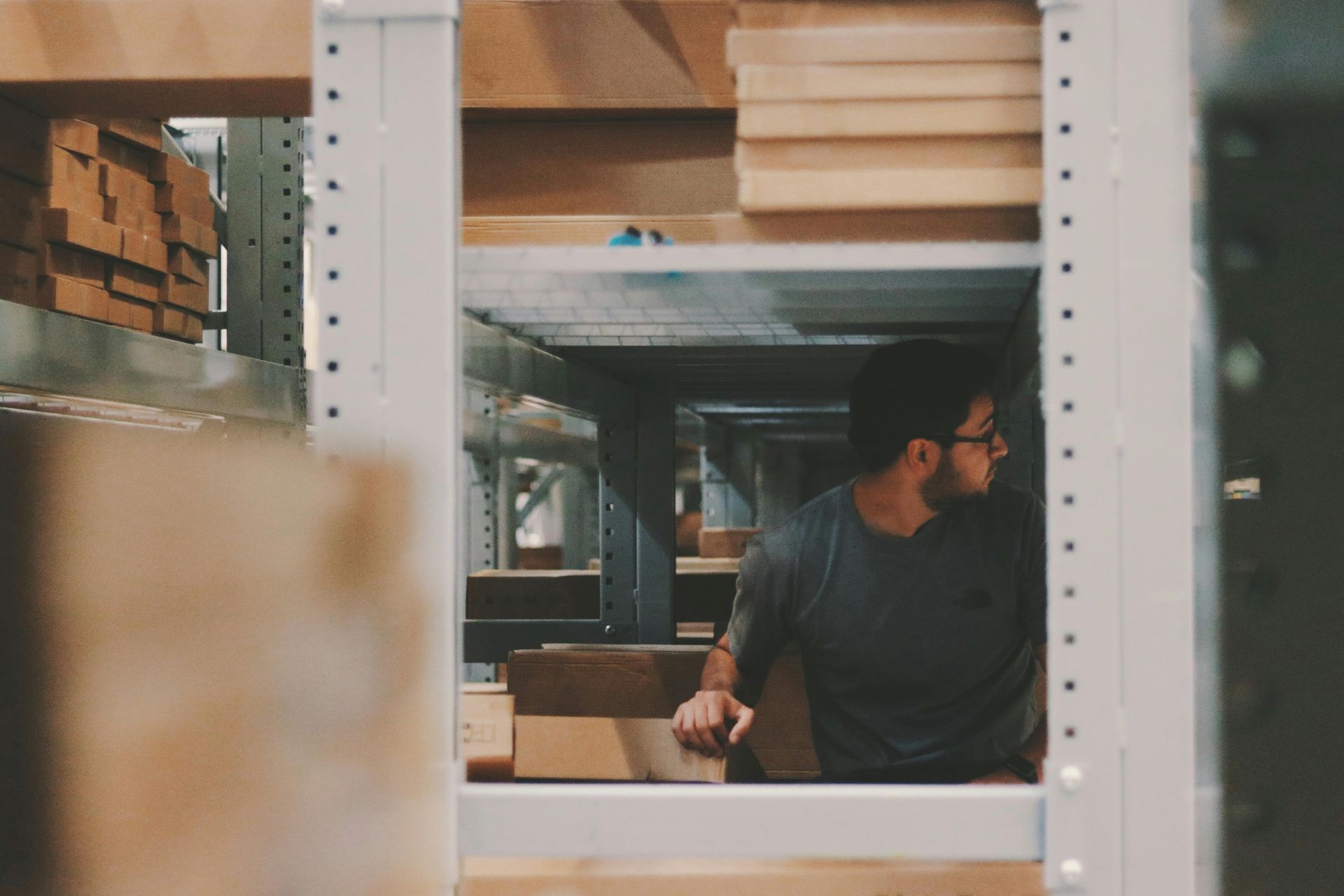 A man is standing in a warehouse looking out of a window.