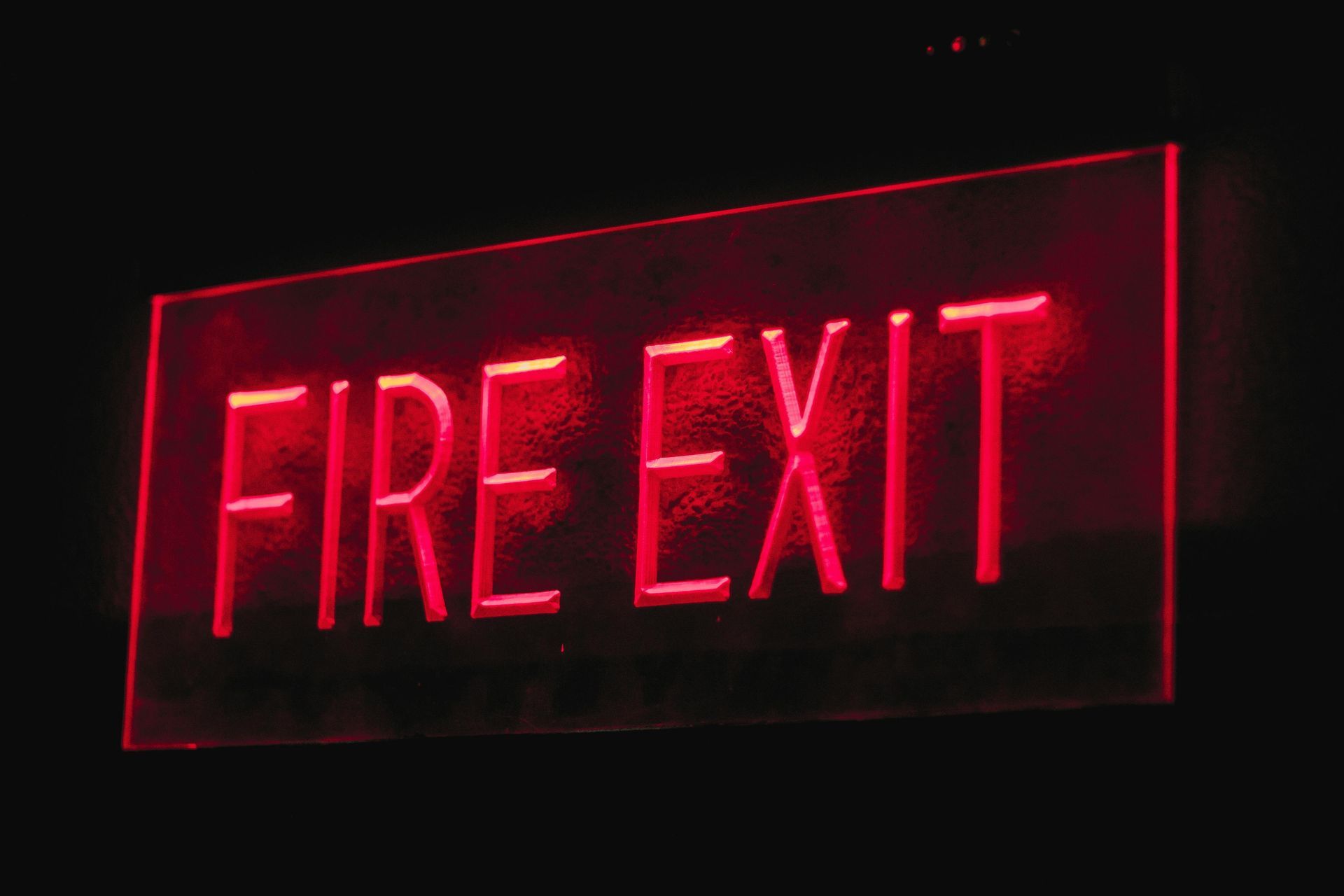 A red fire exit sign is lit up in the dark