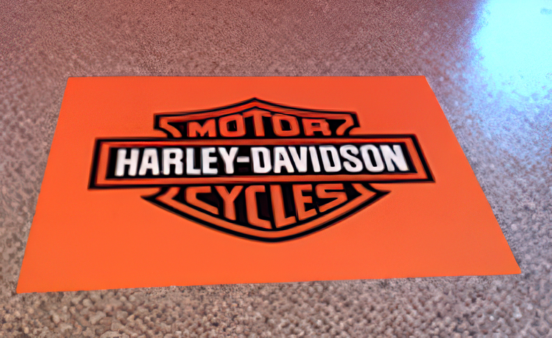 The orange and black Harley-Davidson bar and shield logo printed on a flat surface.