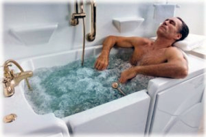 A man is laying in a bathtub filled with water.
