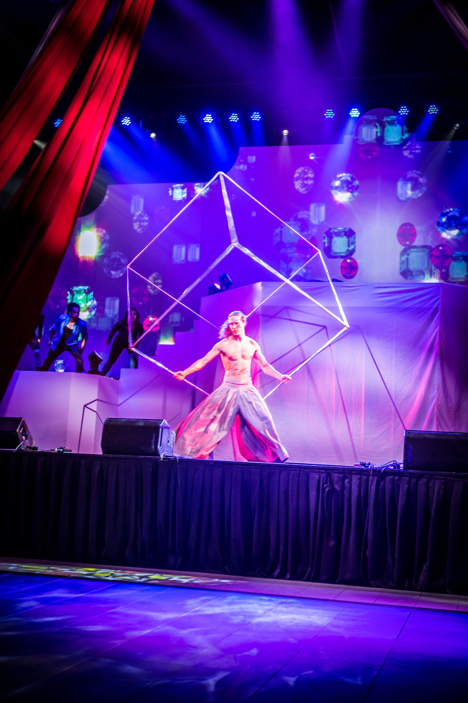 A man is standing on a stage holding a giant cube.