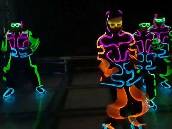 A group of people are dancing in glow in the dark costumes