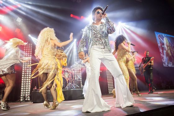 Elvis impersonator and back up dancers perform on stage