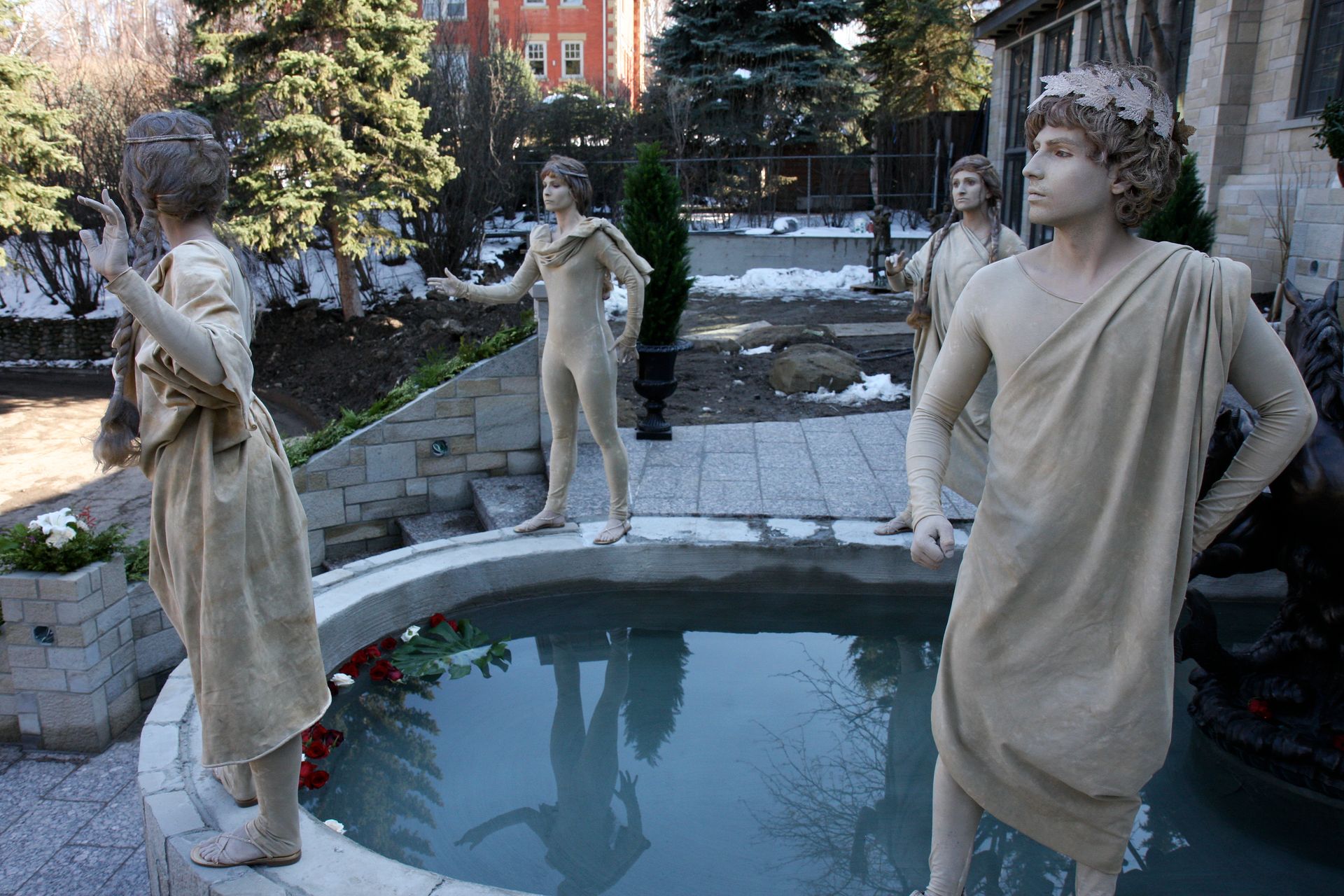 Living statues standing next to a pool