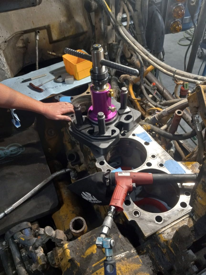 Mechanic working on an engine, using tools, in a garage.