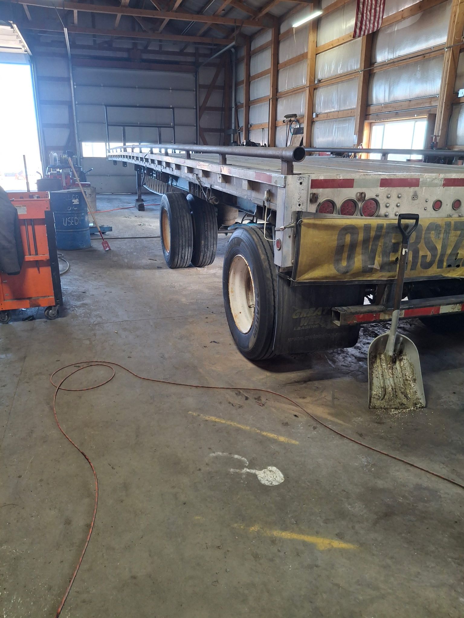 Mechanic working on truck brakes. Tires and tools are on the ground in a repair shop.