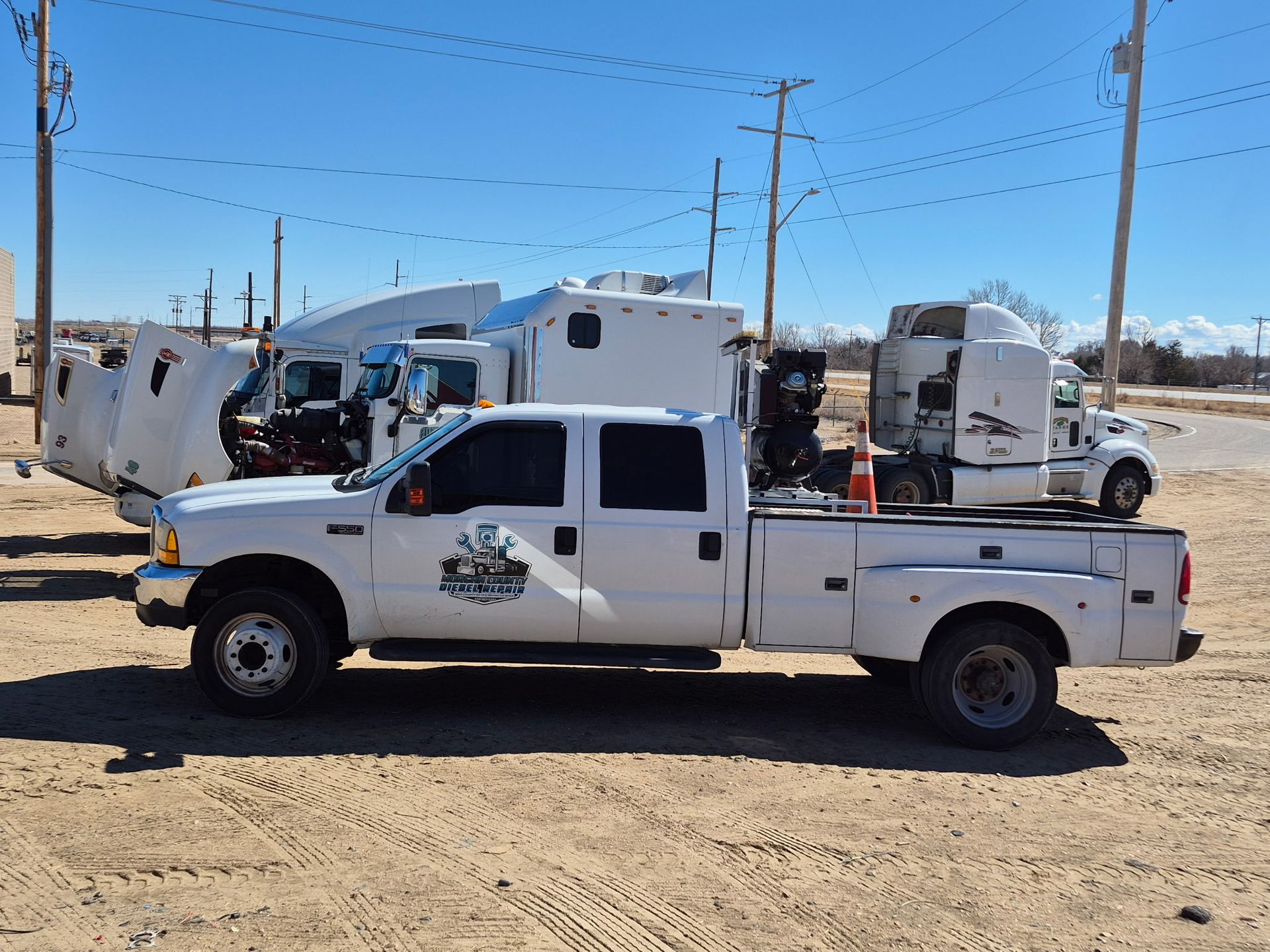 Mechanic in blue overalls and gloves working on a truck engine in a garage.