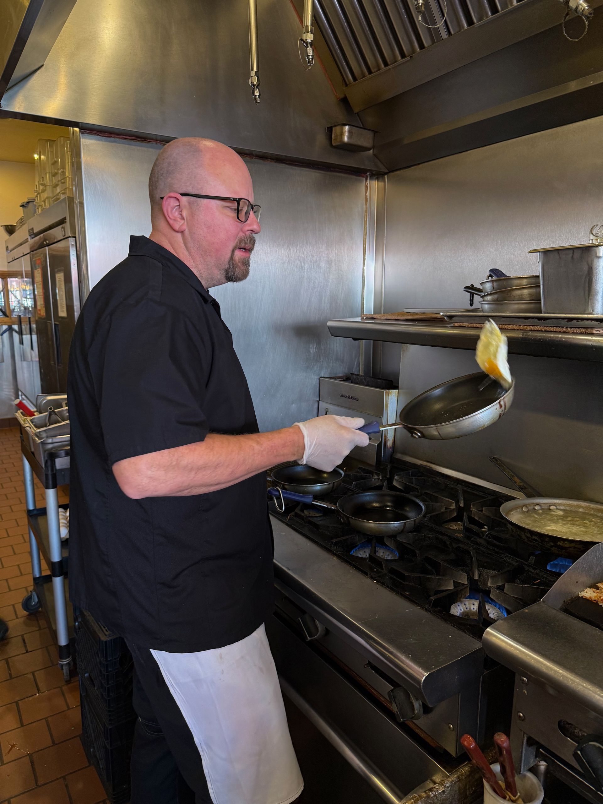 A man is cooking food on a stove in a kitchen