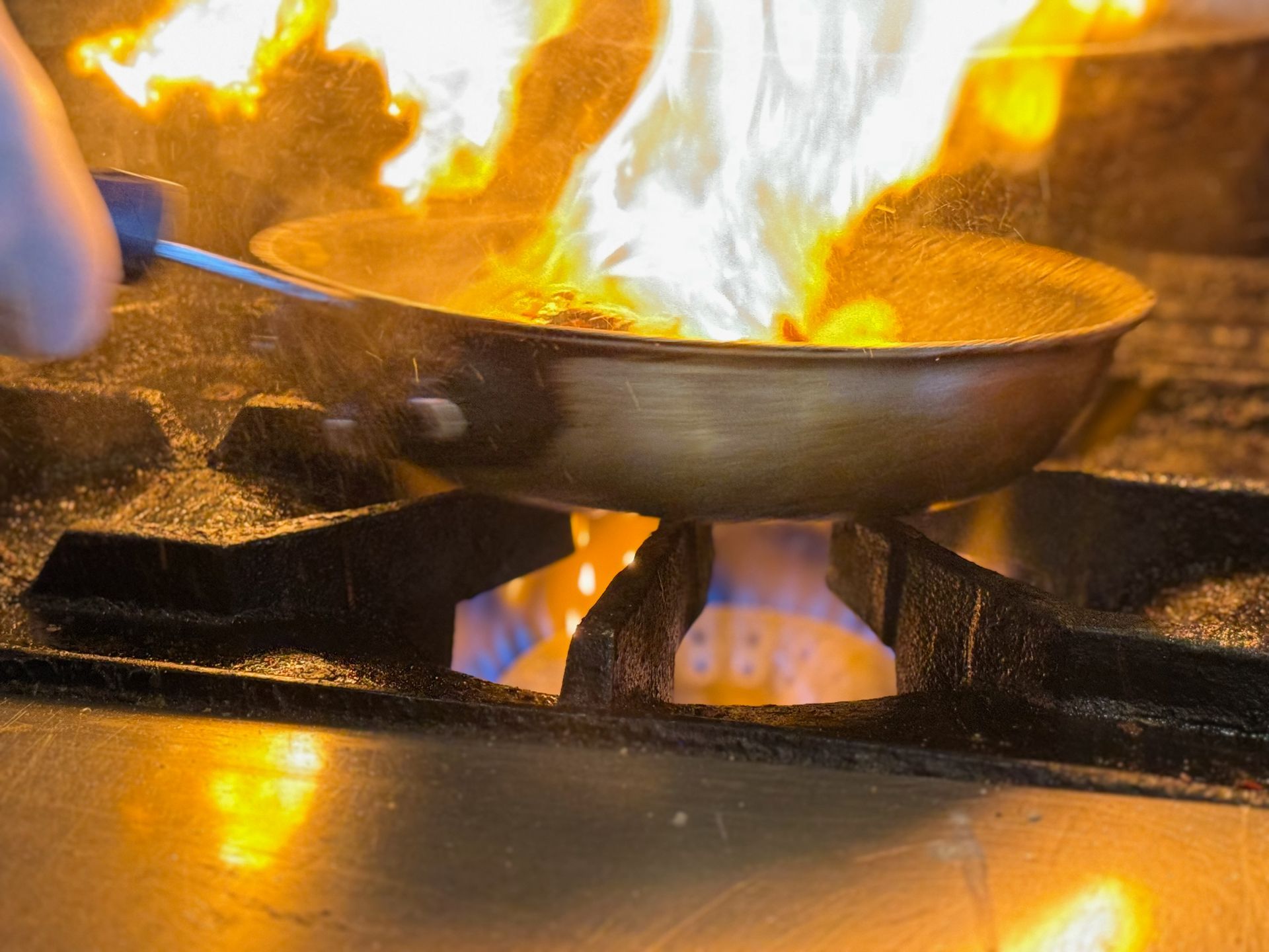 A person is cooking food in a frying pan on a stove.