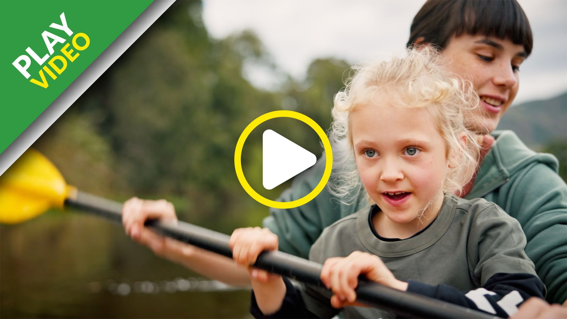 A woman is teaching a little girl how to paddle a kayak.