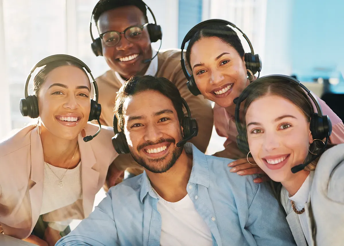 Smiling customer service team wearing headsets, looking at the camera.