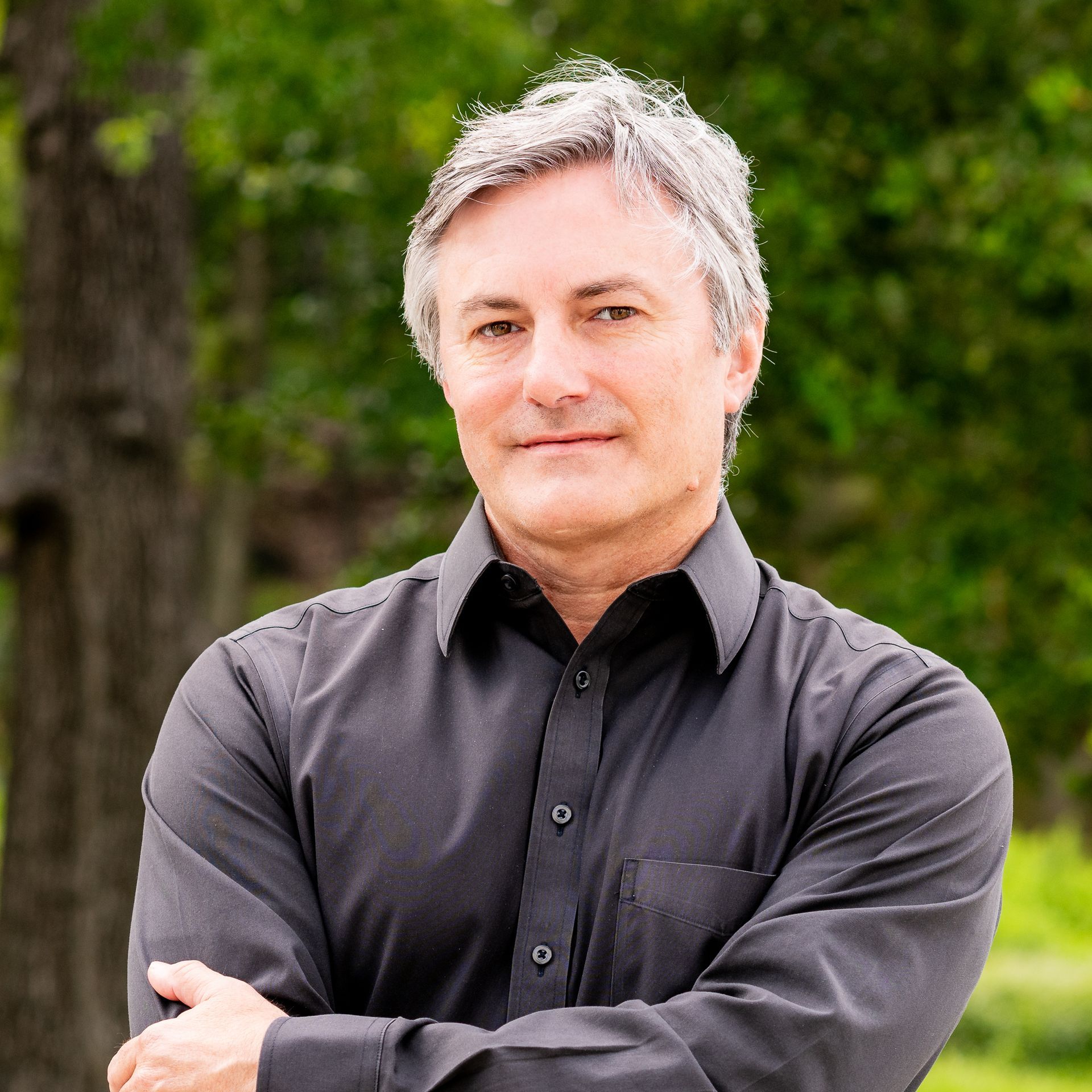 A man in a black shirt is standing with his arms crossed.