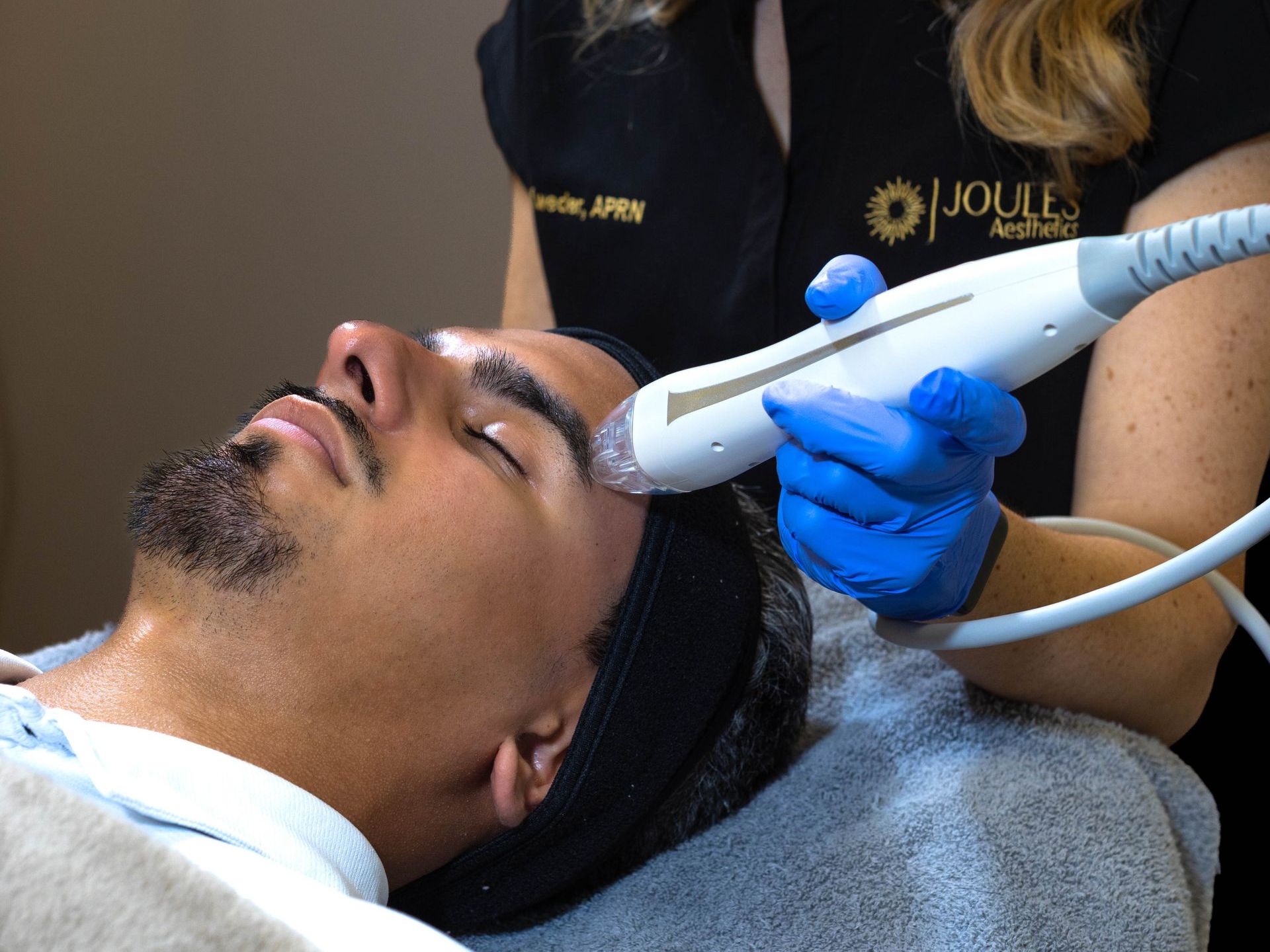 A man is getting a treatment on his face by a woman wearing blue gloves.
