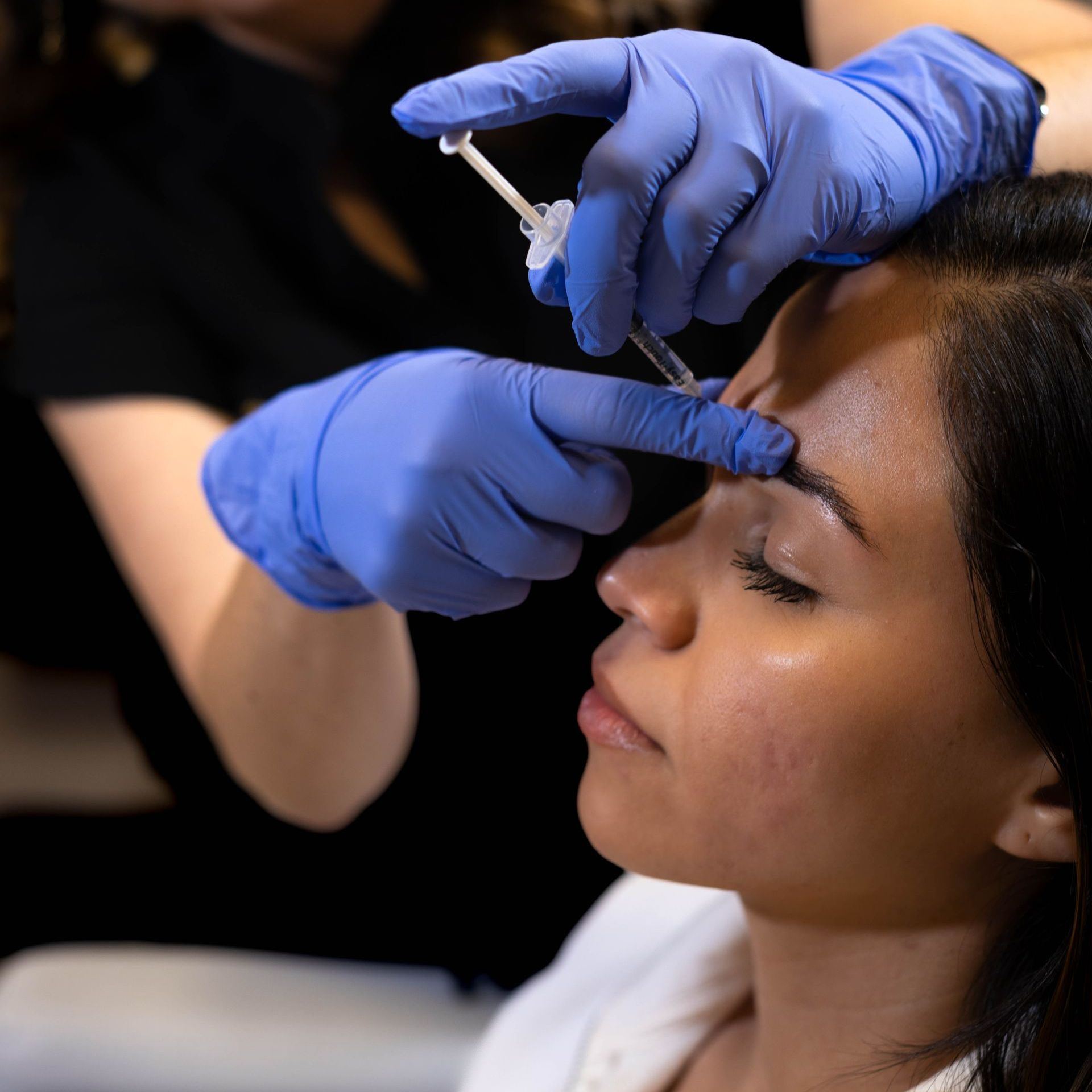 A woman is getting a botox injection in his face.