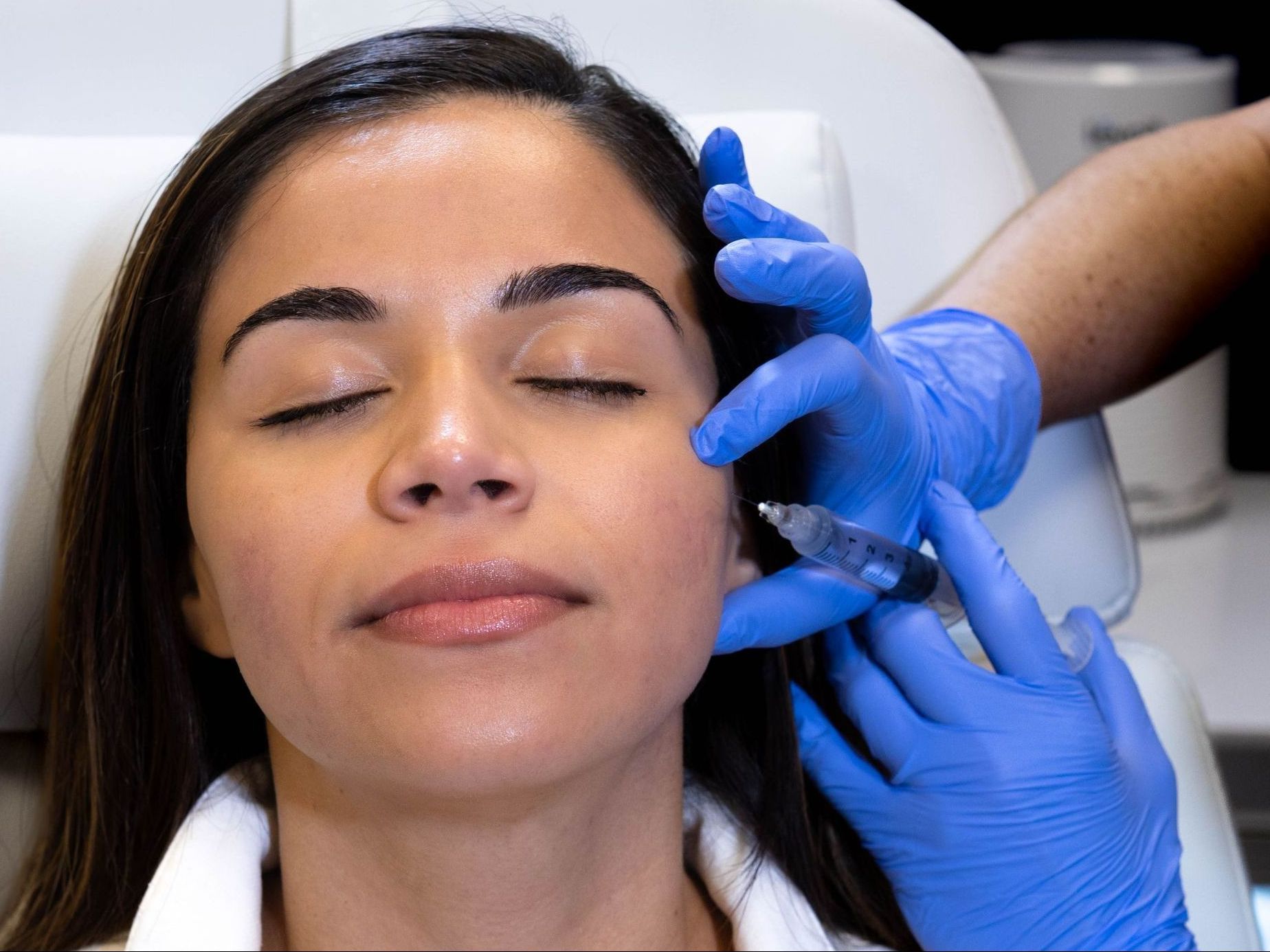 A woman is getting a botox injection in her face