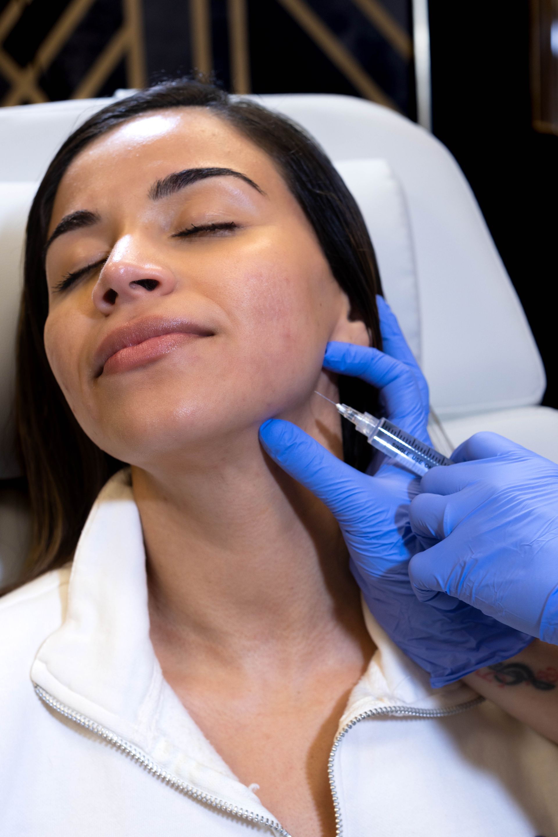 A woman is getting a botox injection in her face