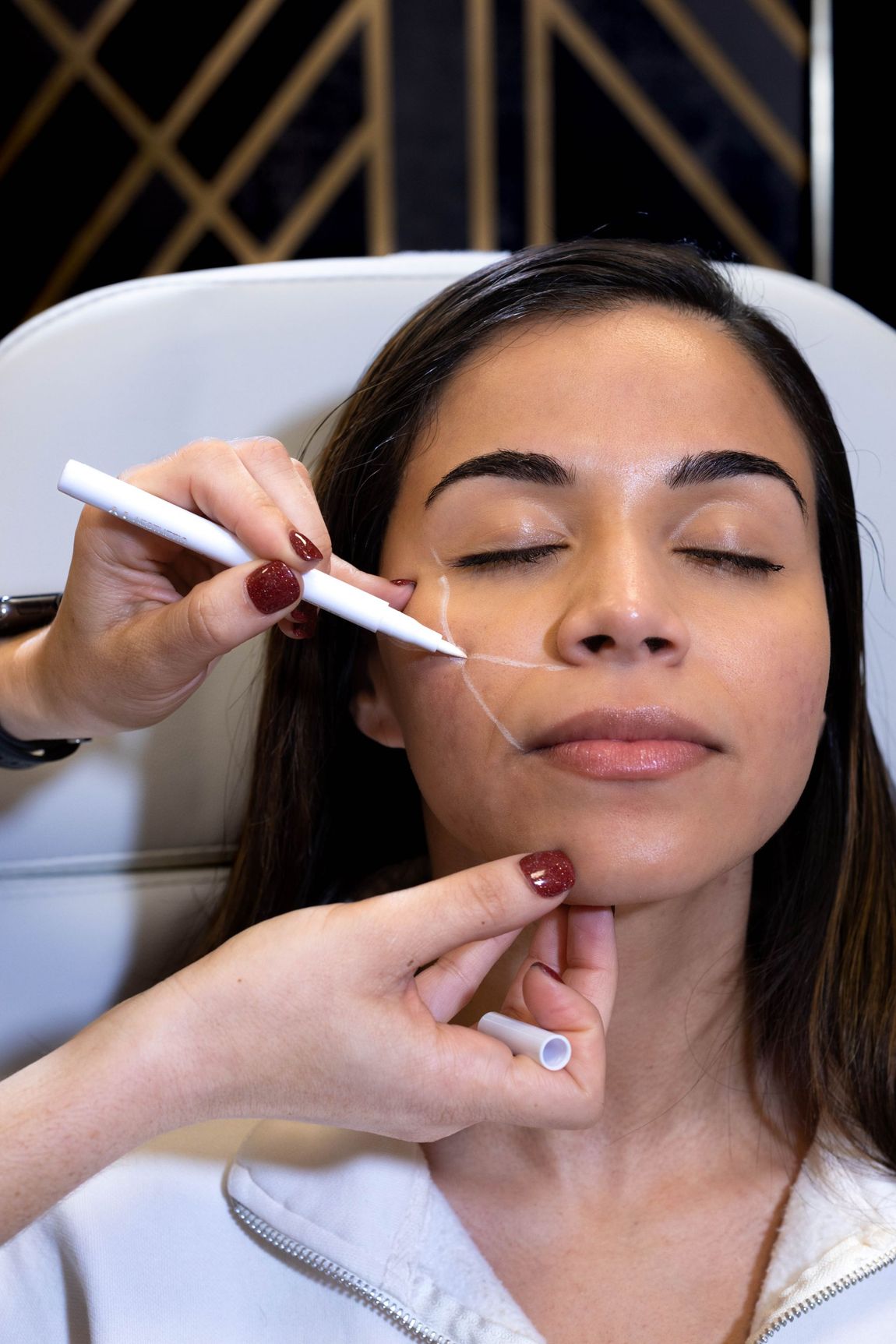 A woman is getting a tattoo on her face.
