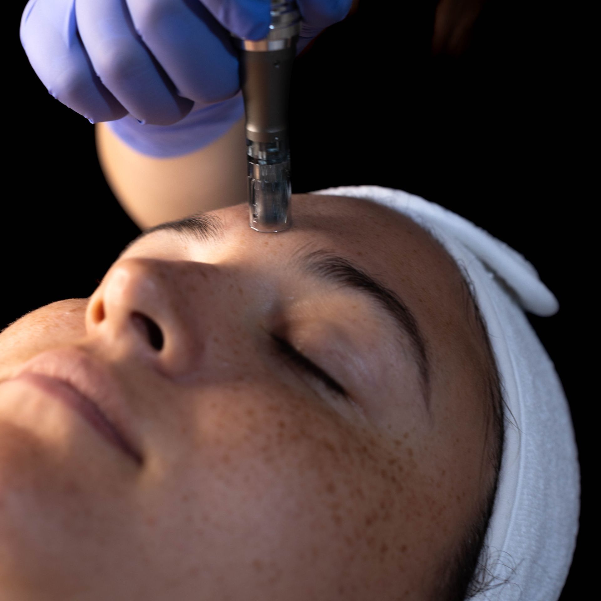 A woman with her eyes closed is getting a treatment on her face