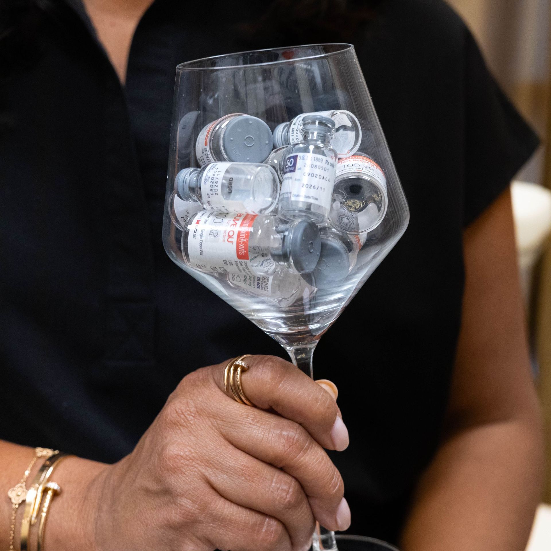 A woman is holding a wine glass filled with bottles.