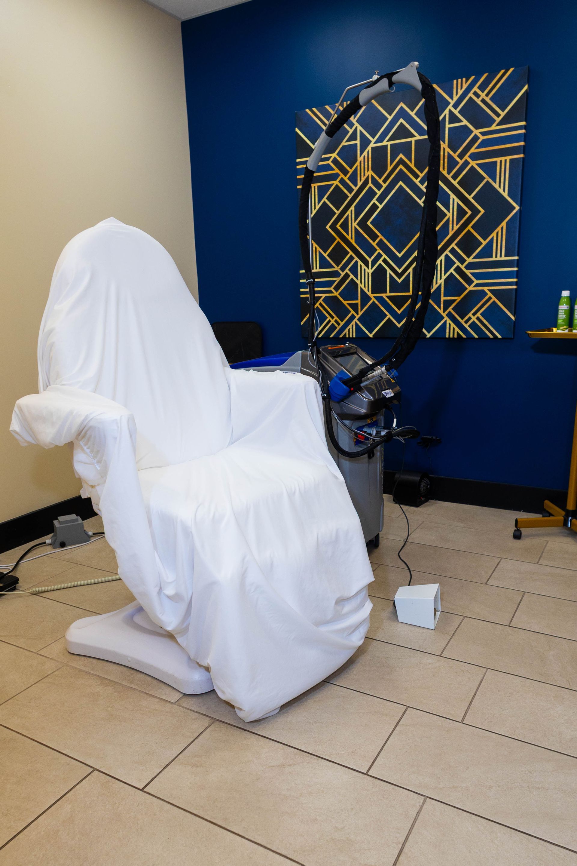 A chair is wrapped in a white cloth in a room with a blue wall.