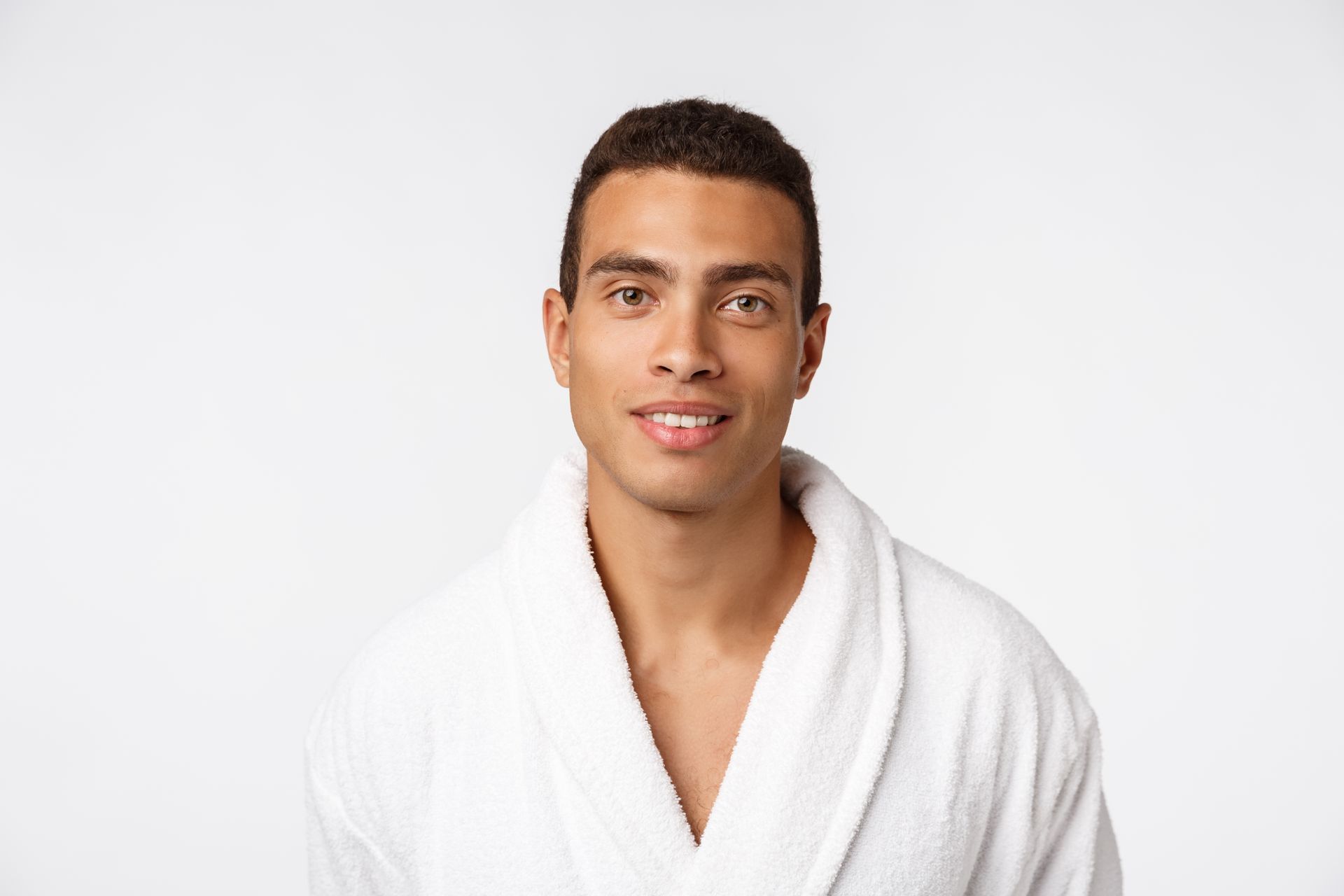 A man in a white robe is smiling and looking at the camera.