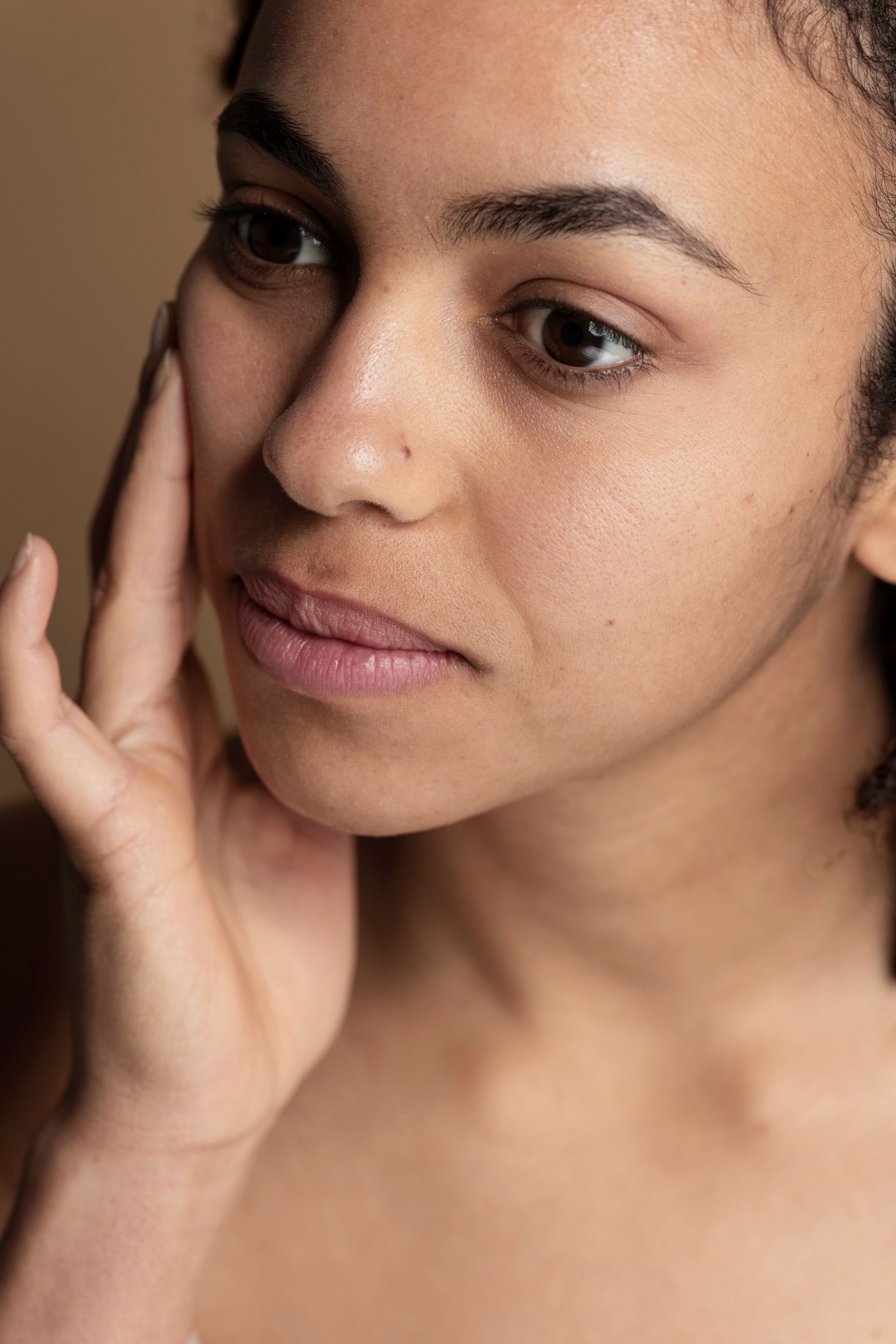 A close-up portrait of a person with brown hair, looking thoughtfully to the side with a neutral expression.