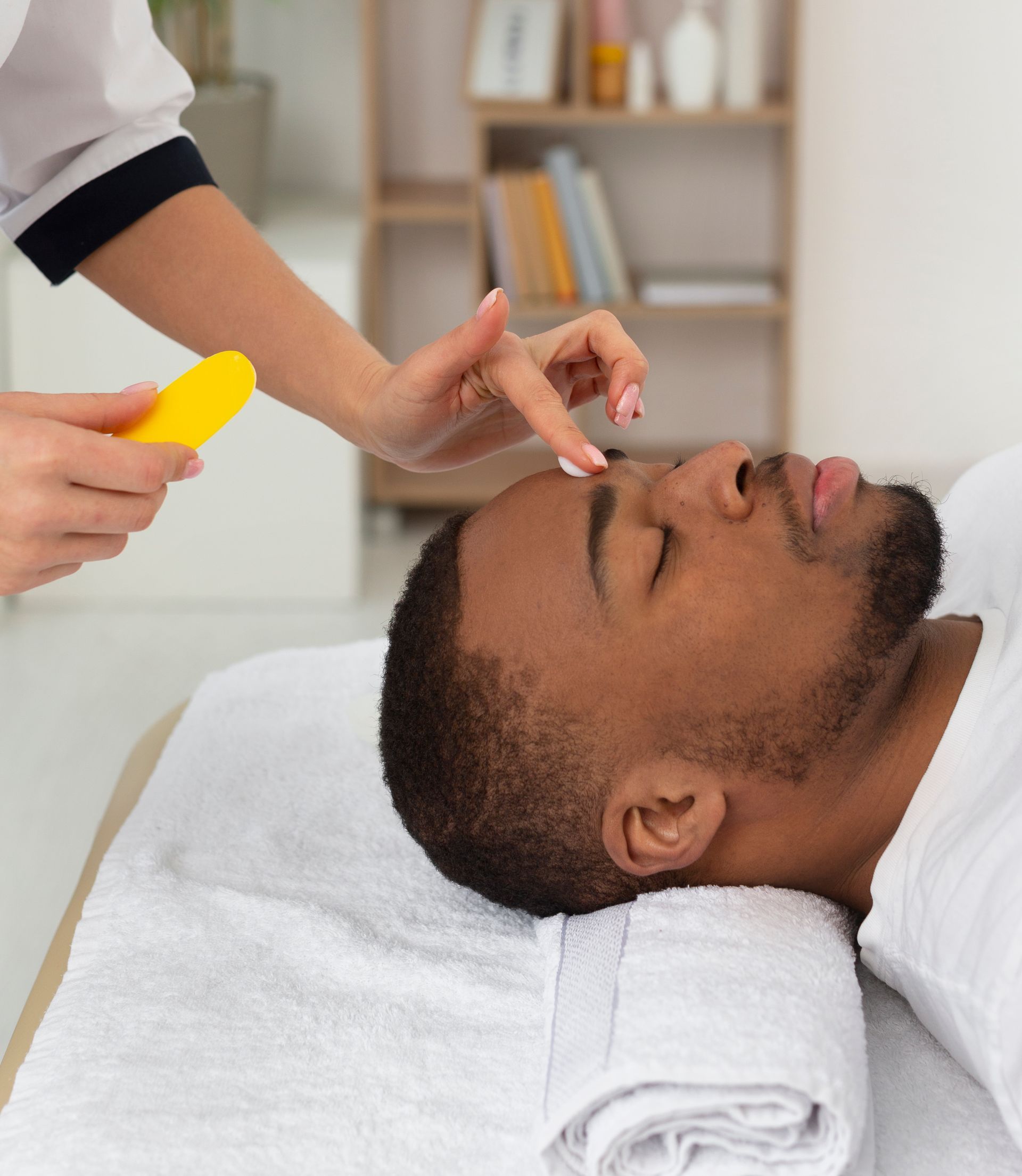 A man is laying on a bed getting a massage from a woman.