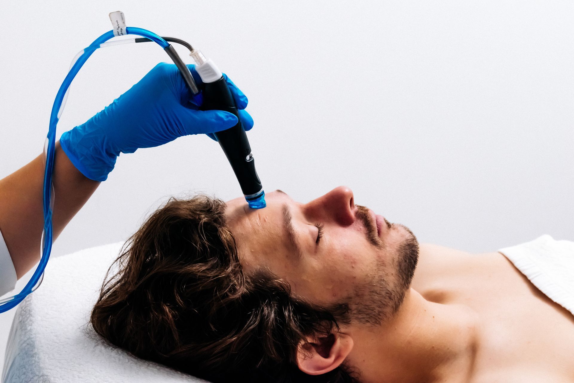 A woman with curly hair is smiling and touching her face.
