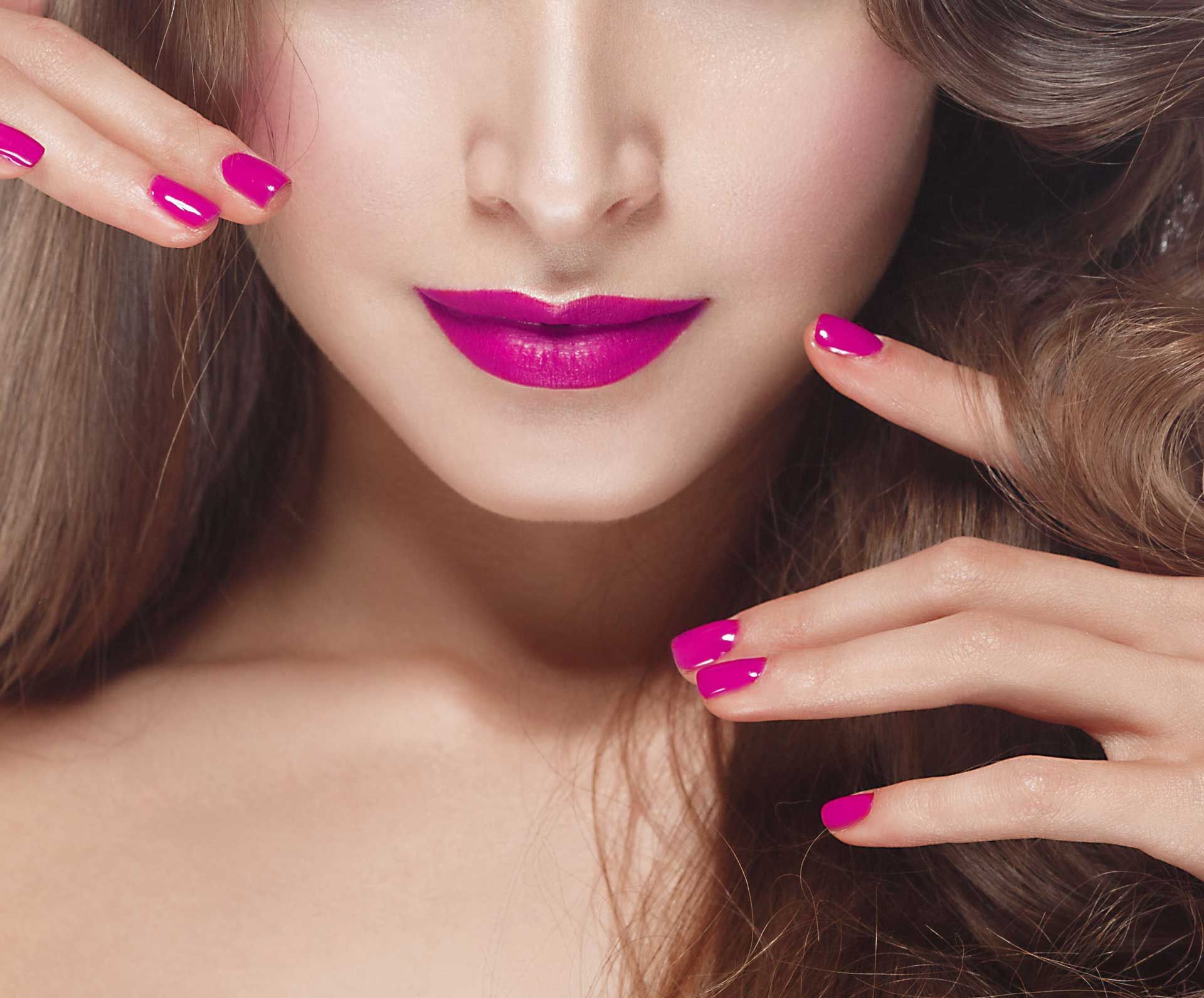 A close up of a woman 's face with pink lipstick and pink nails