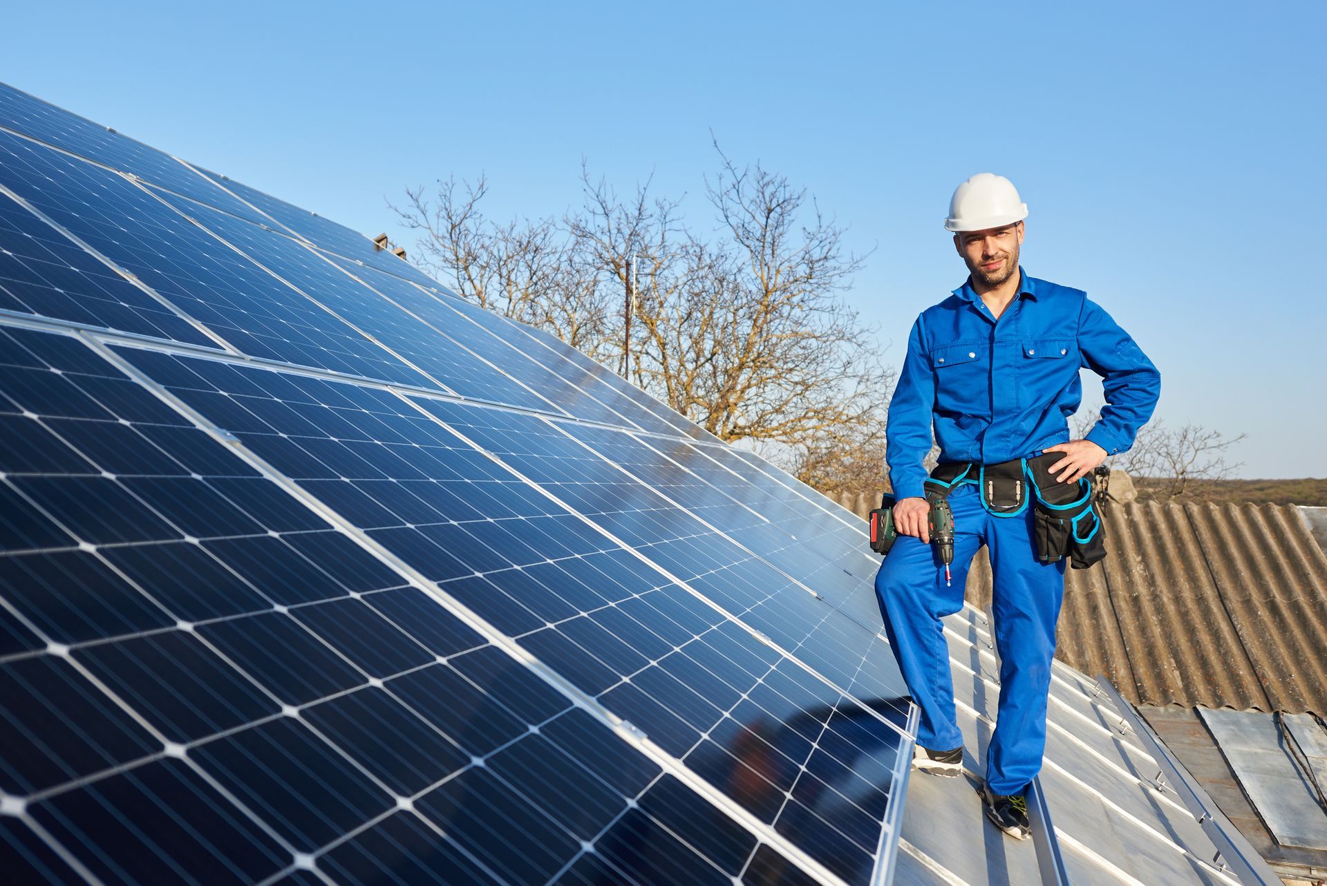 A man is standing on top of a roof with solar panels.