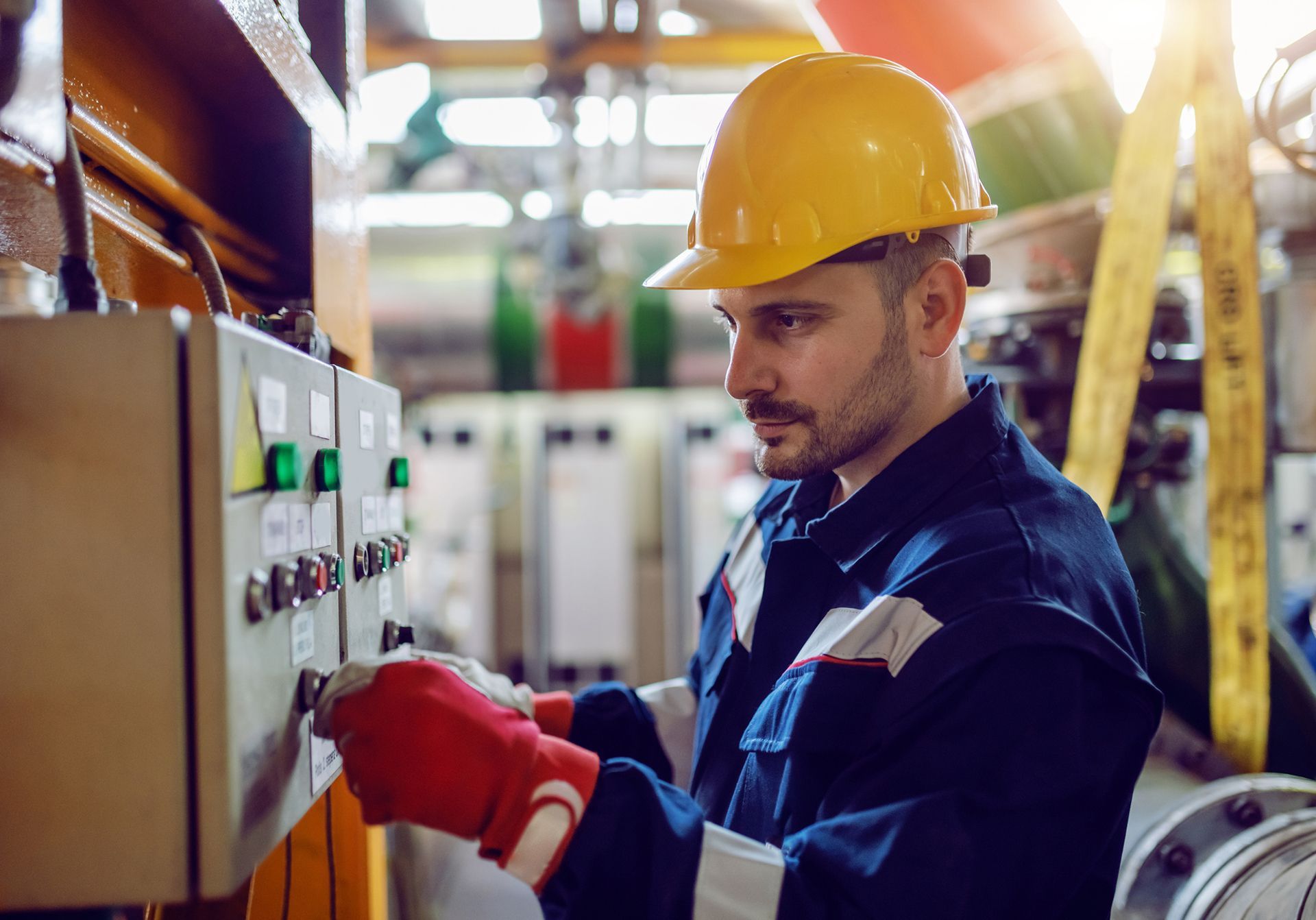Energy plant worker in working clothes and with helmet on head turning on switch.