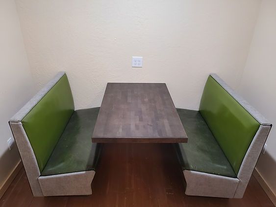A wooden table with two green benches in a room.