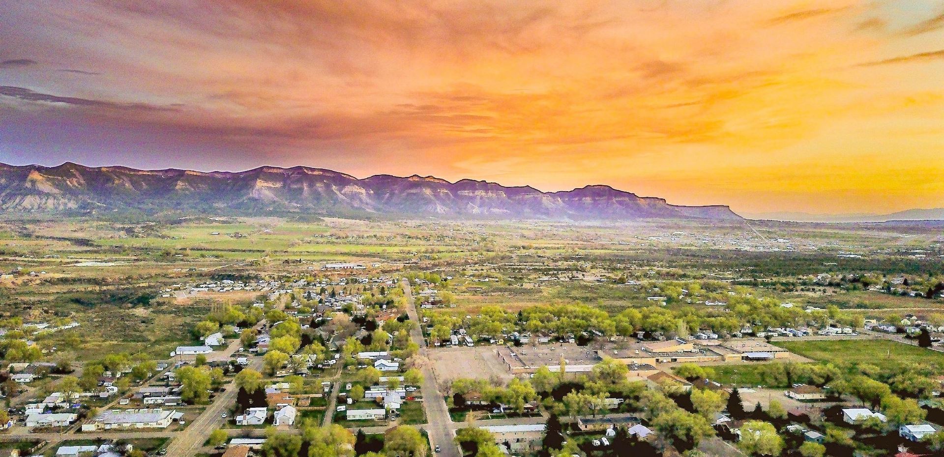 An aerial view of a city at sunset with mountains in the background.