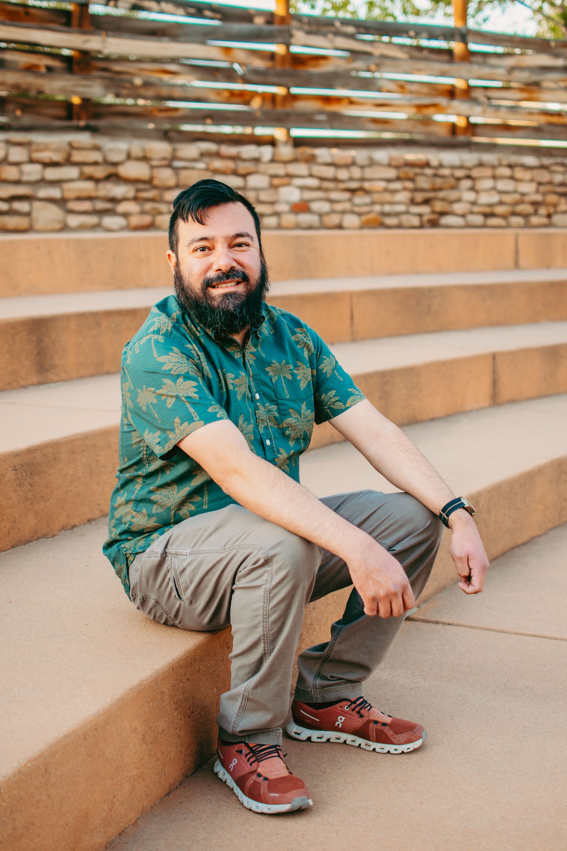 A woman wearing a necklace and earrings is standing in front of a yellow background.