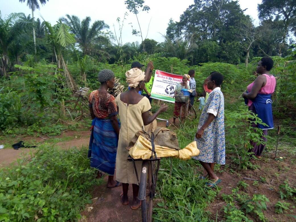 A group of people are standing around a bicycle in a field.