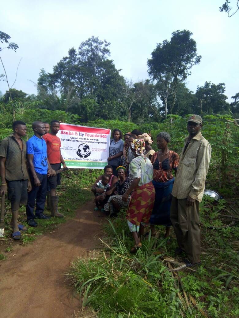 A group of people are standing around a sign in a field.