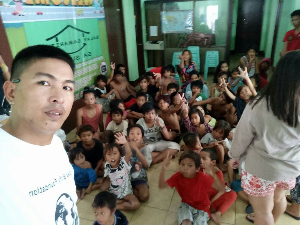 A man is taking a selfie with a group of children