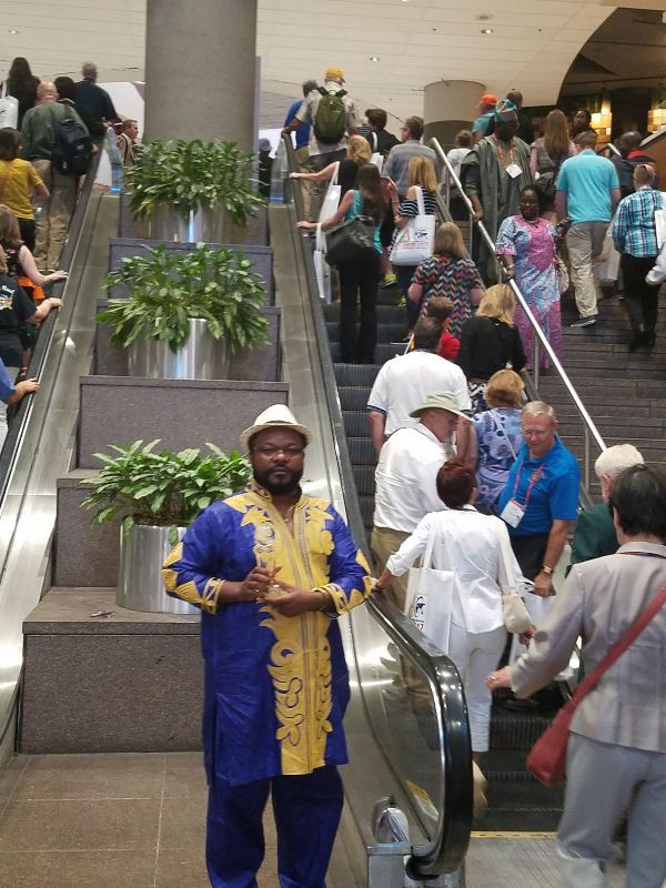 A man in a blue and yellow outfit is standing next to an escalator